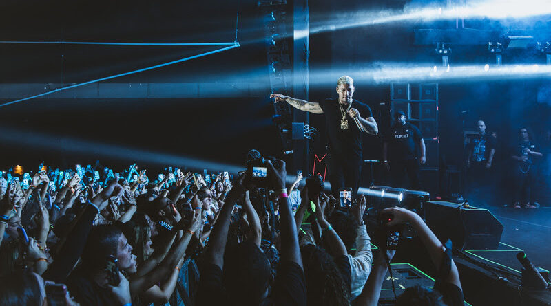 Imagem mostra homem em palco cantando para multidão