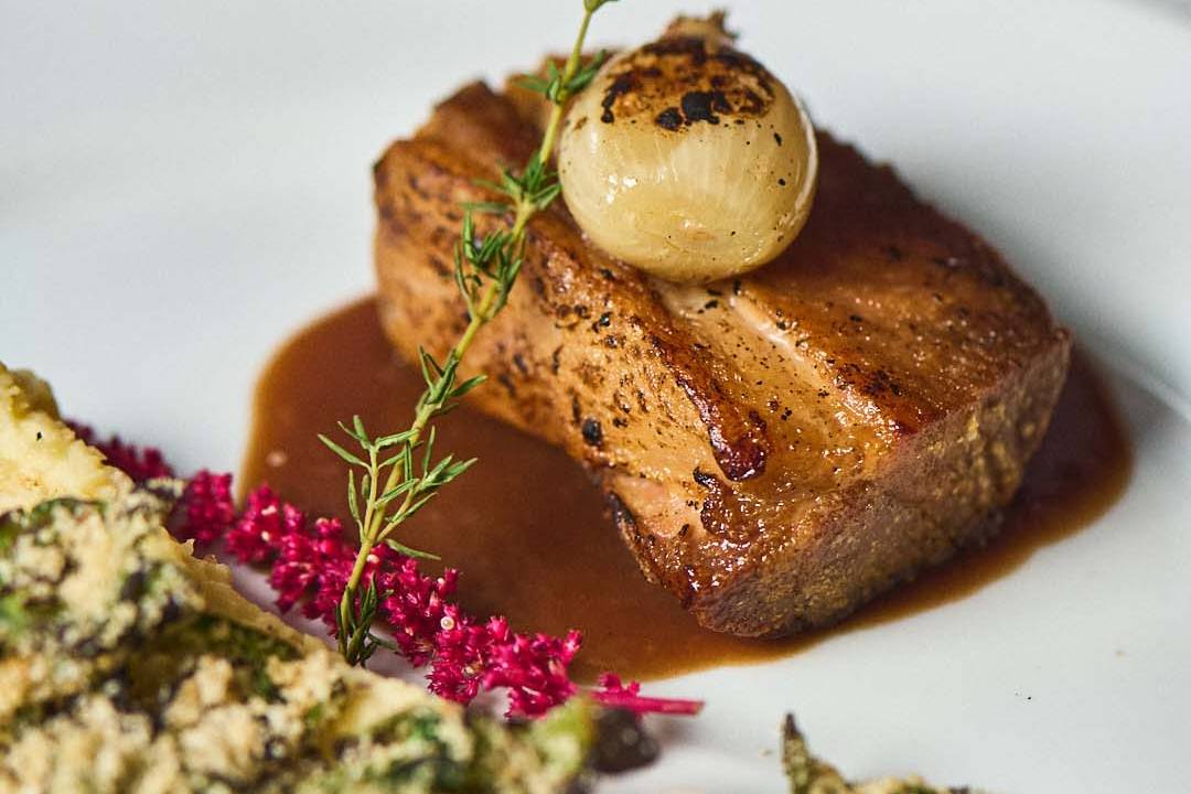 Prato com paleta de porco, musseline de batata, chalota tostada e farofa de espinafre