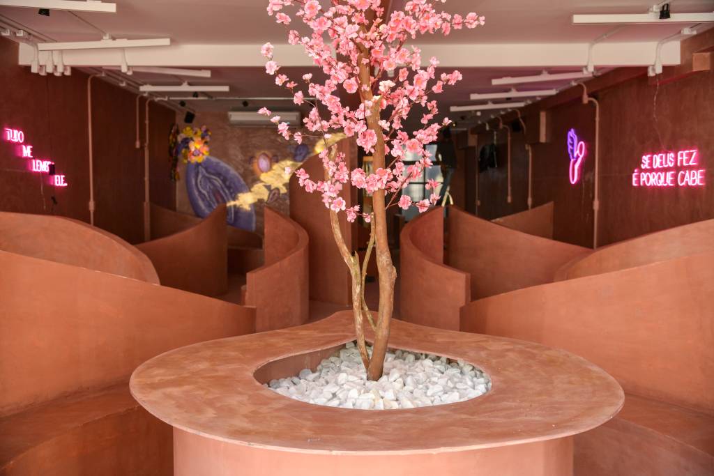 Foto de ambiente com árvore rosa no centro de banco coletivo e paredes curvas em drywall.