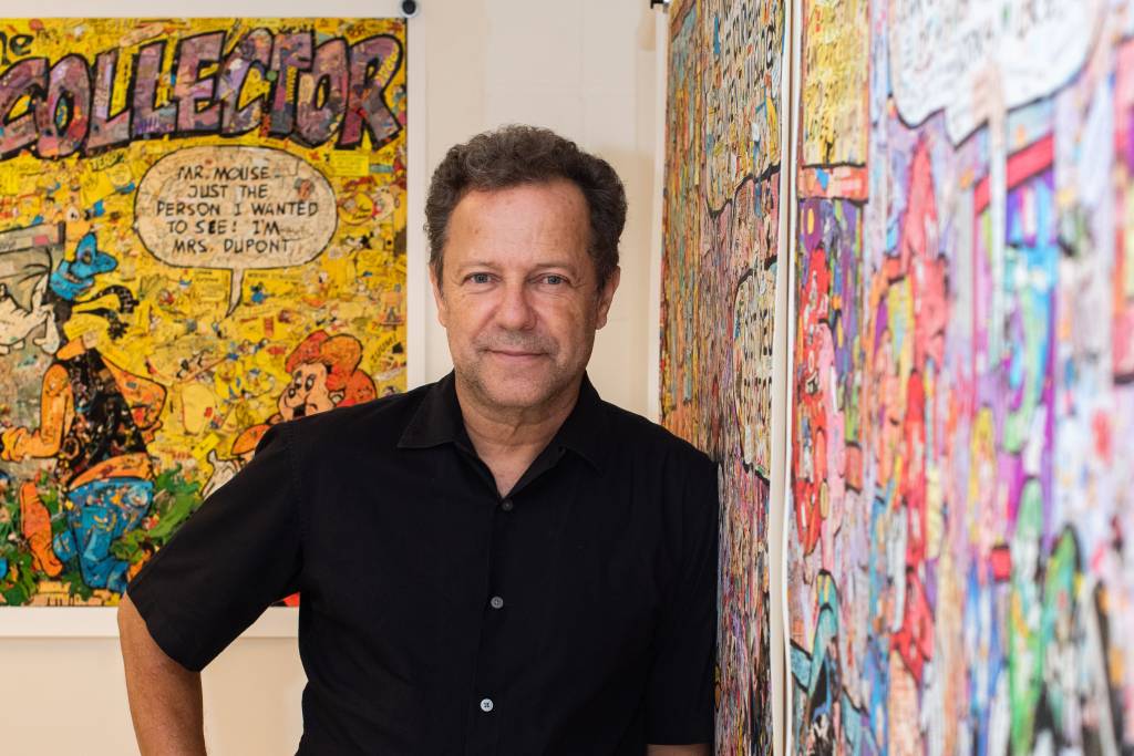 SP-ARTE Vik Muniz Imagem mostra homem de camisa preta apoiado em parede com quadro colorido