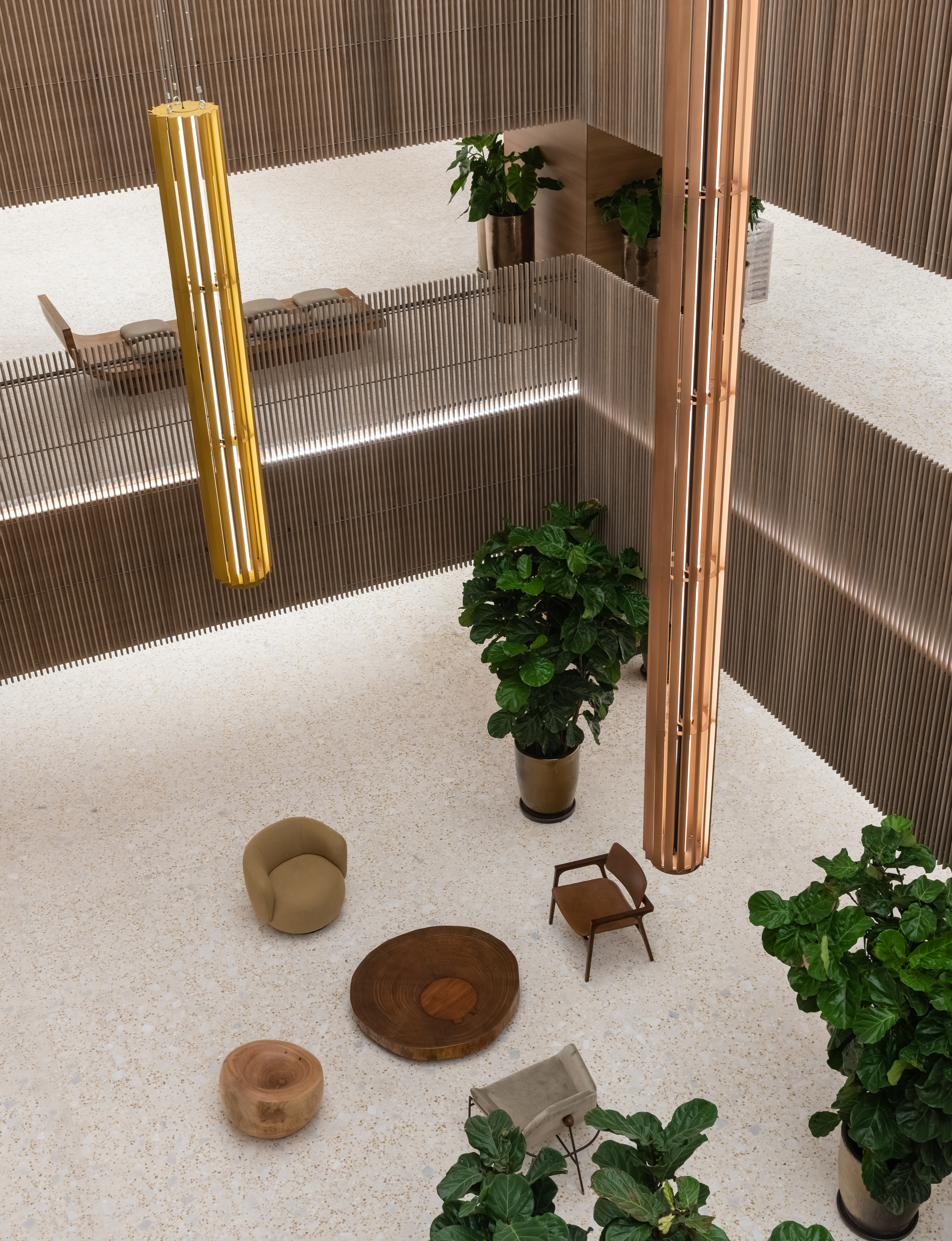 La foto de arriba muestra un espacio claro con tonos de madera en un centro comercial.  Cabe ver butacas en color madera y dos plantas.