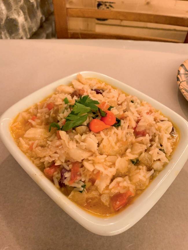 Espinheta de Bacalhau O Mirandês Tigela de porcelana quadrada contendo bacalhau desfiado com azeite, vinagre, cebola, cebolinha e salsa sobre mesa