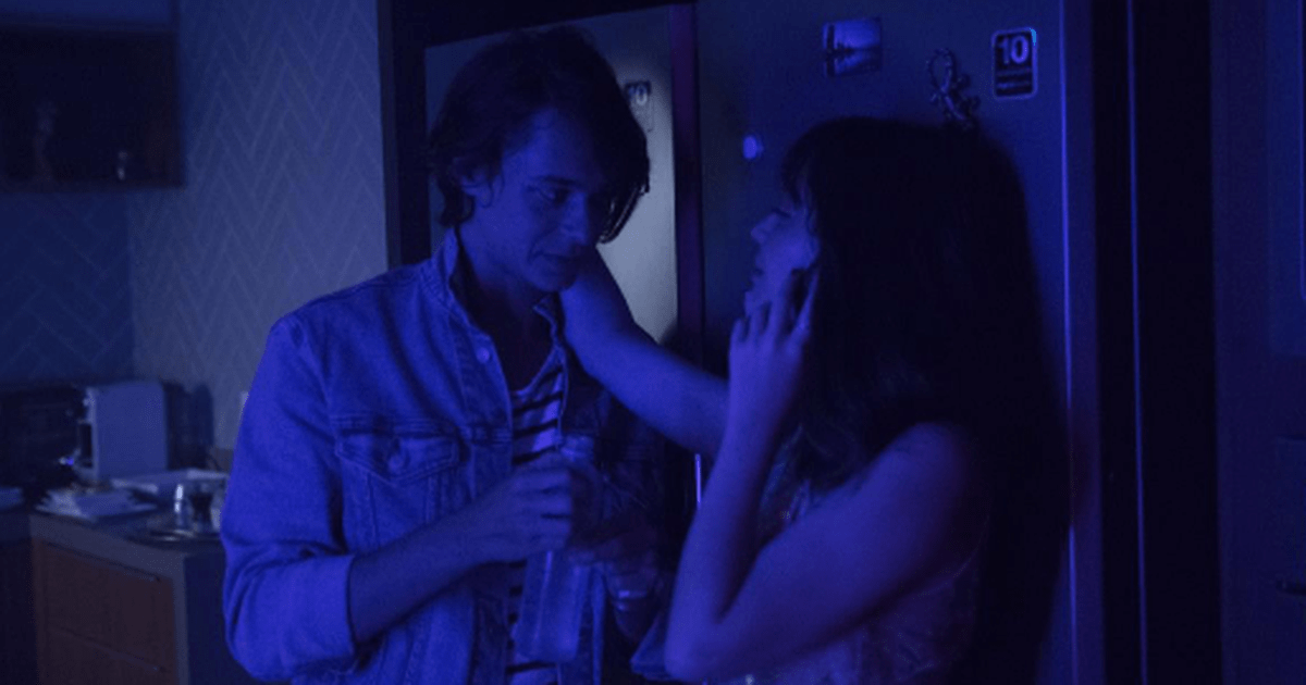 Dois jovens juntos em festa em cenário azul