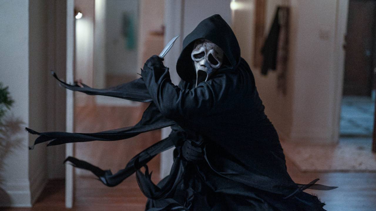 Ghostface, vestido com roupa preta e máscara de terror, com uma faca na mão