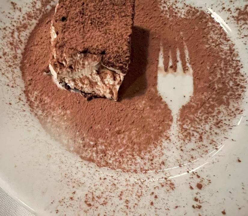 Tiramisu com chocolate em pó sobre prato de porcelana