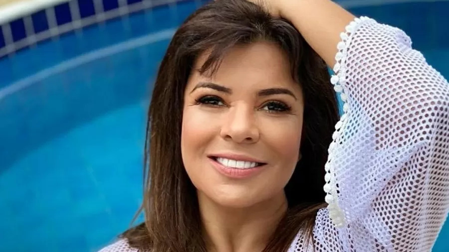 Mara maravilha com blusa de crochê branco com piscina azul ao fundo