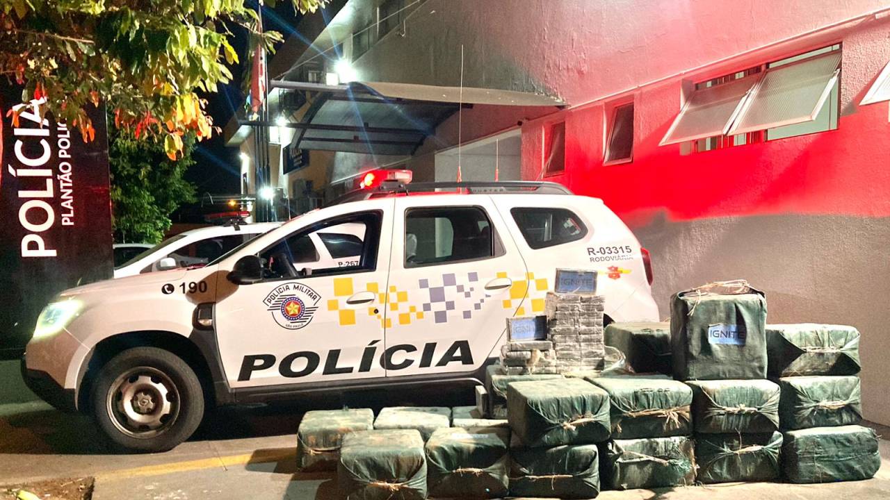 pacotes de cocaína e viaturas da polícia militar ao fundo