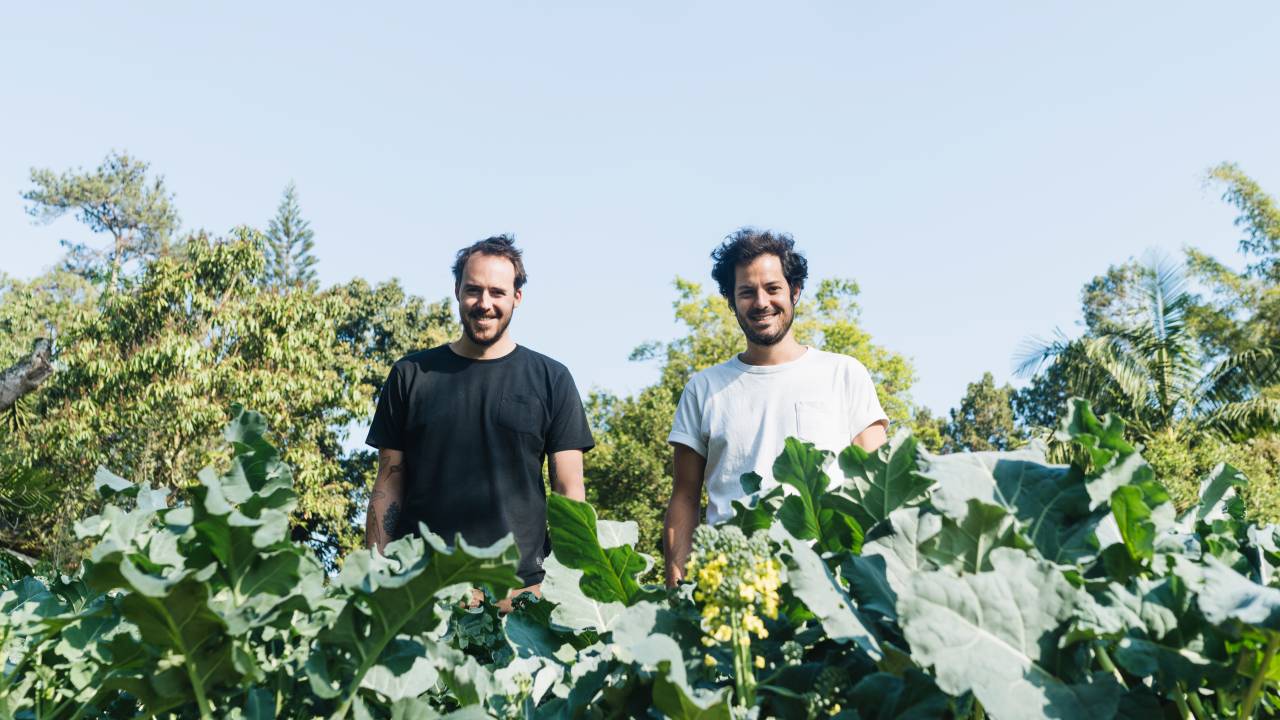 Dois homens brancos lado a lado num jardim.