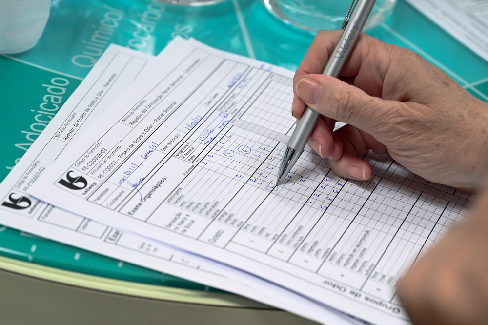 Sabesp – Degustação Mão completando papel com tabela da Sabesp.