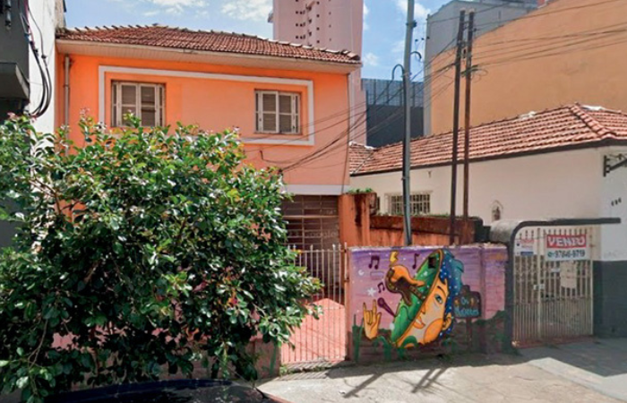 Imagem mostra casa laranja com grafites no muro