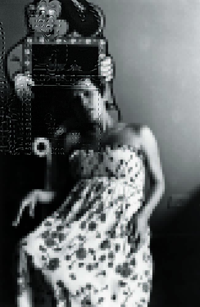 Imagem em preto e branco mostra mulher sentada em poltrona