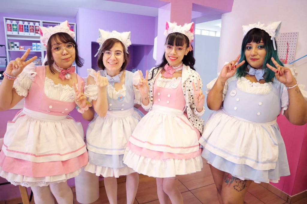 Quatro mulheres vestidas de cosplay em cafeteria colorida.