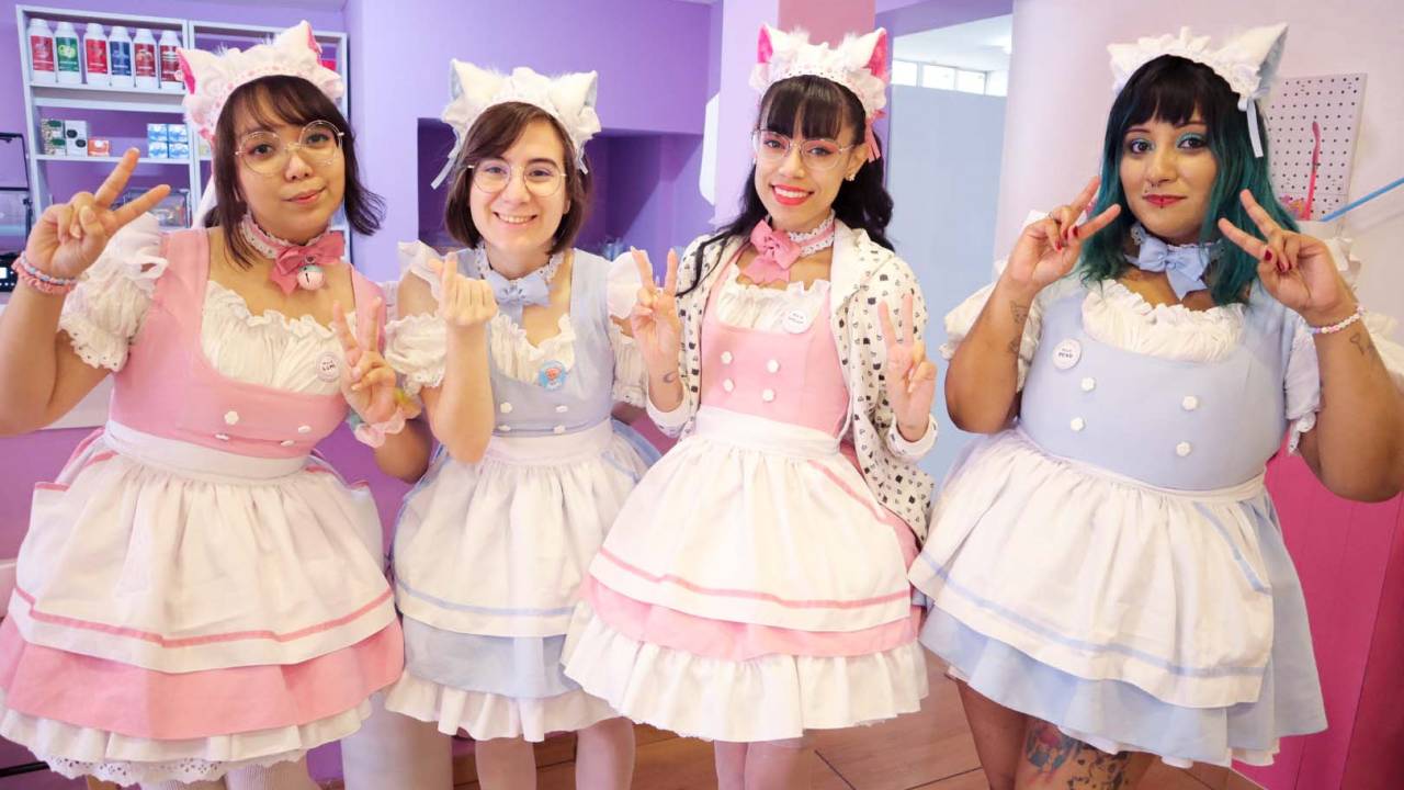 Quatro mulheres vestidas de cosplay em cafeteria colorida.