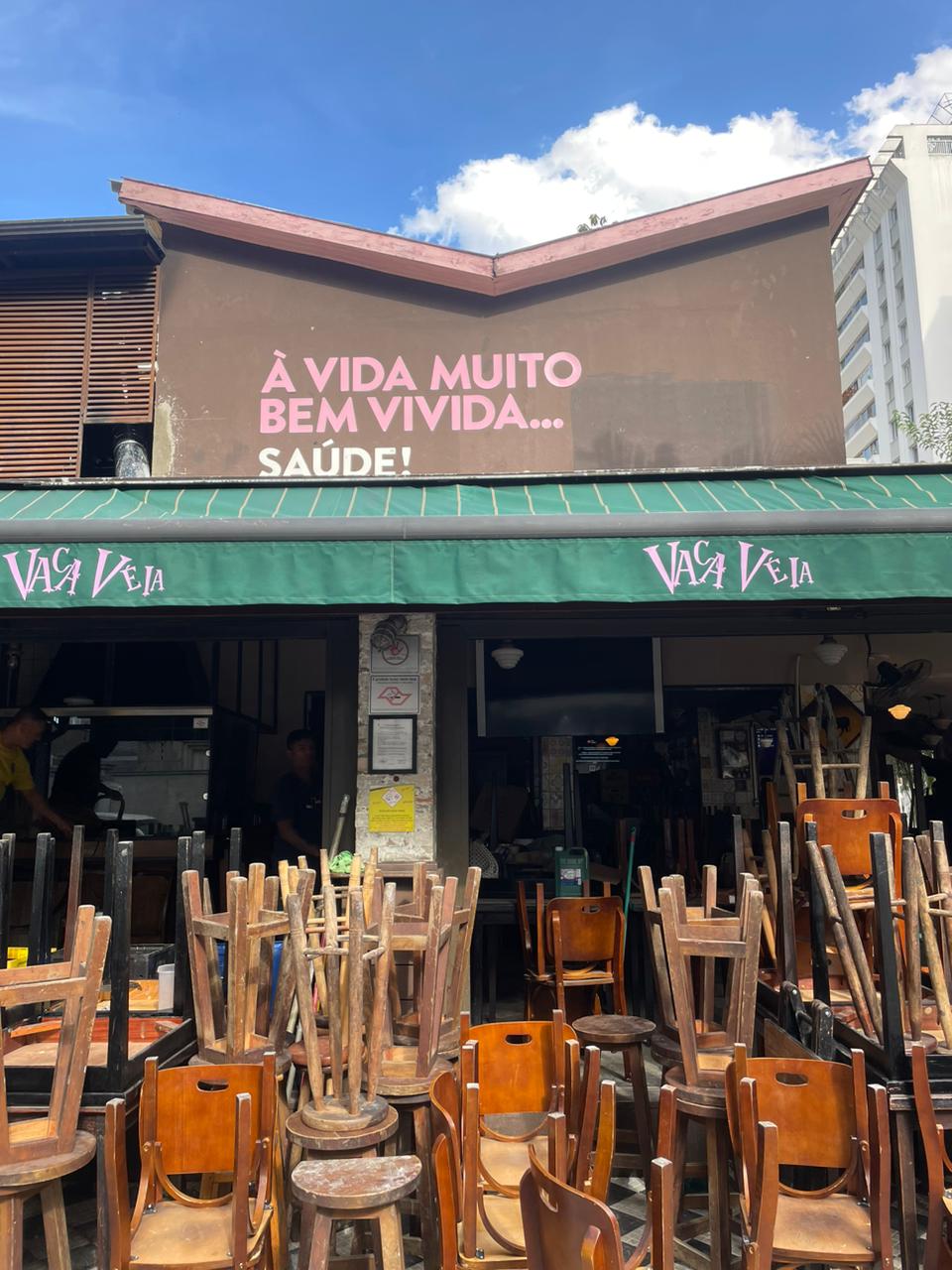 Fachada do bar Vaca Veia com vários bancos empilhados virados para cima.