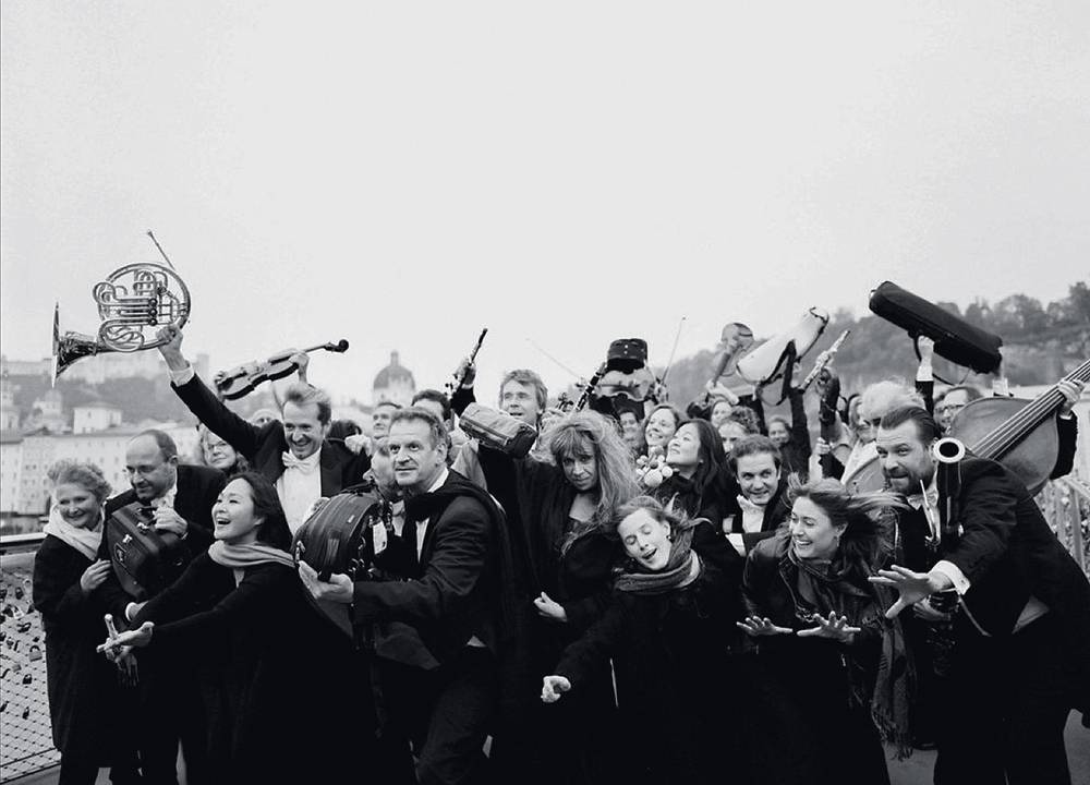 Imagem em preto e branco mostra diversos músicos segurando instrumentos de orquestra