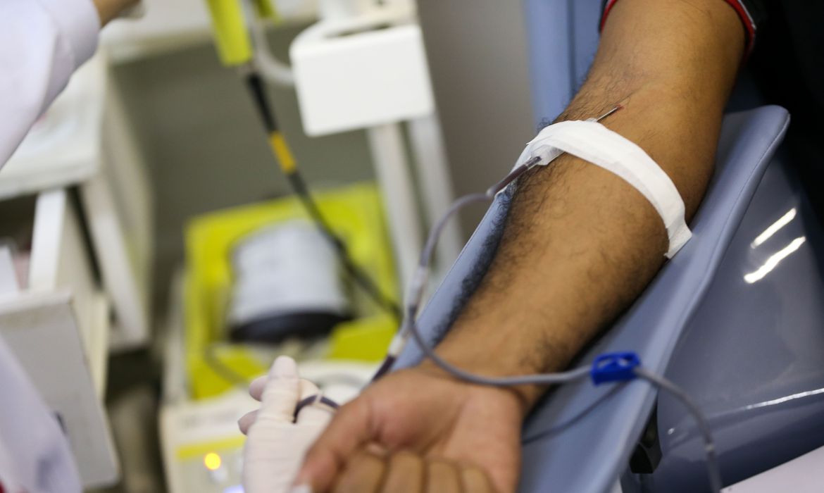 Uma agulha enfiada no braço de um homem que está doando sangue