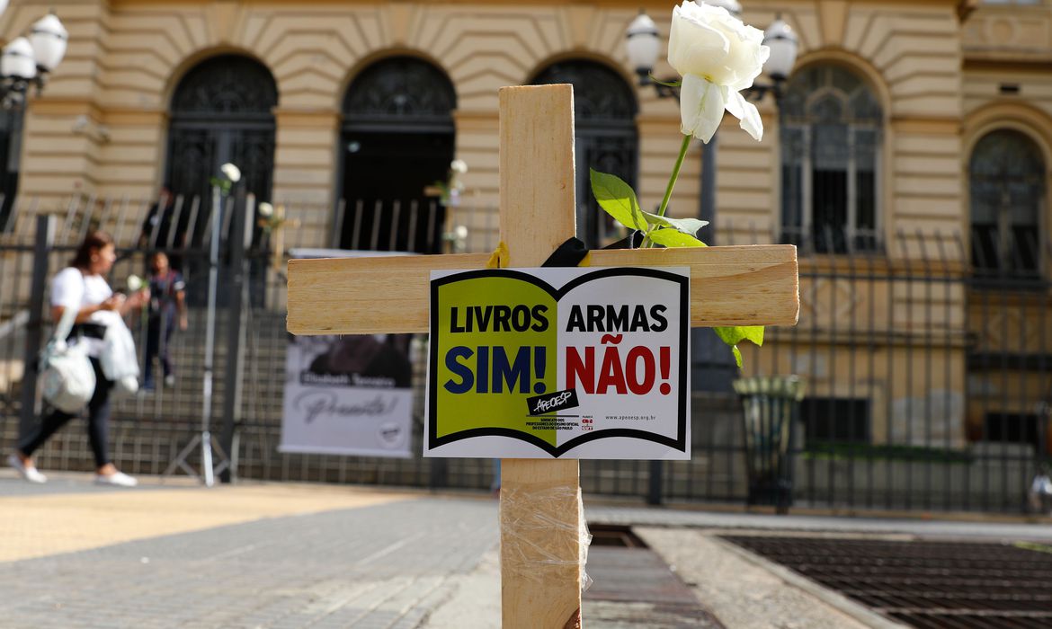 uma cruz de madeira com uma placa que diz "livros sim, armas não"