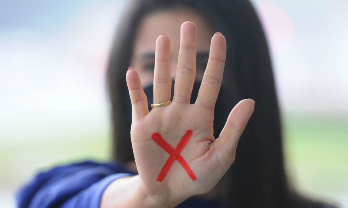 uma mulher mostrando a palma da mão com um X vermelho dentro