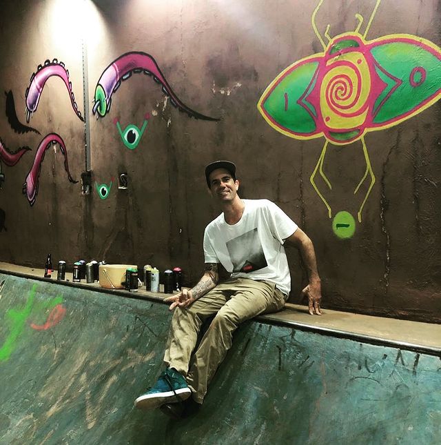um homem branco sentado em uma rampa de skate