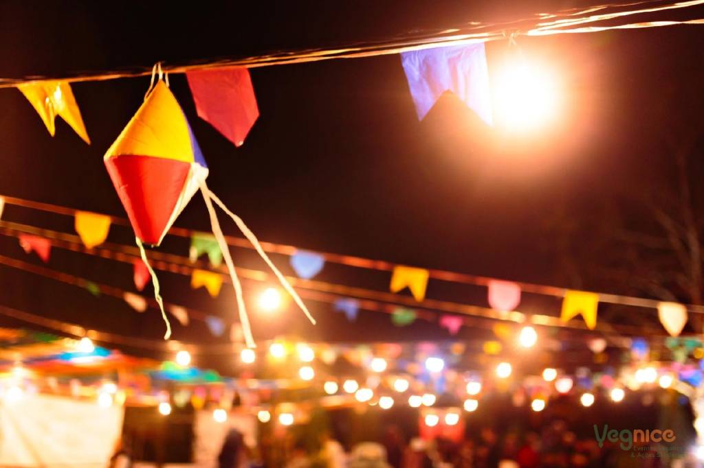 Pequeno balão colorido e fileiras de bandeirinhas aparecem em destaque à noite.