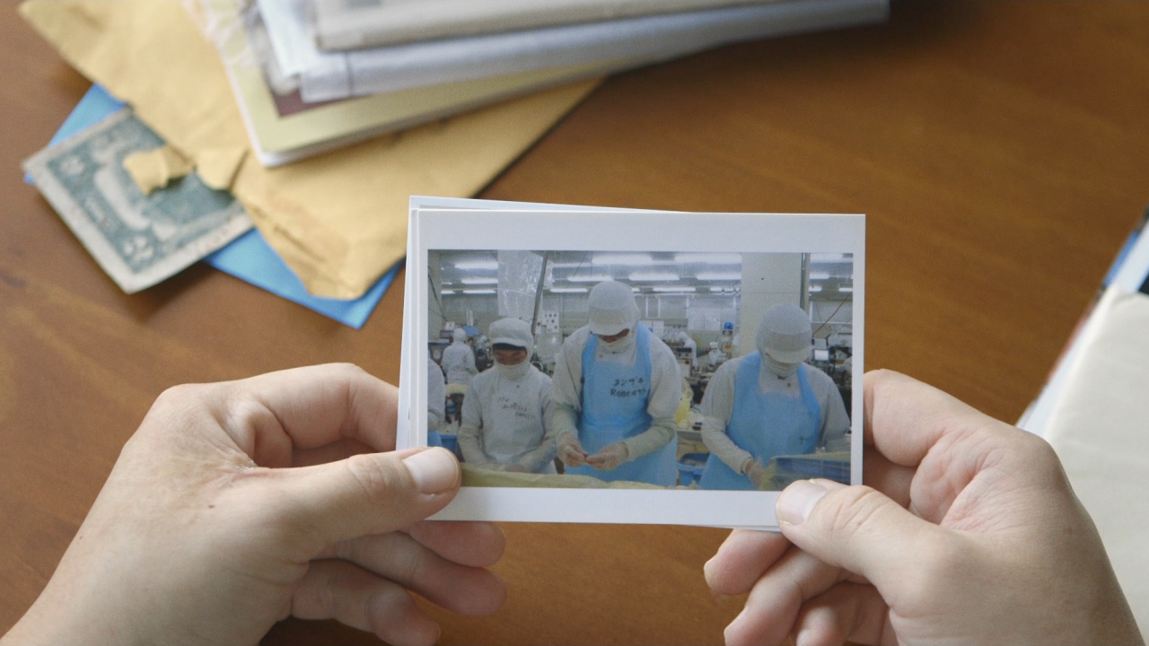 Mãos seguram uma foto de trabalhadores de uma fábrica no Japão