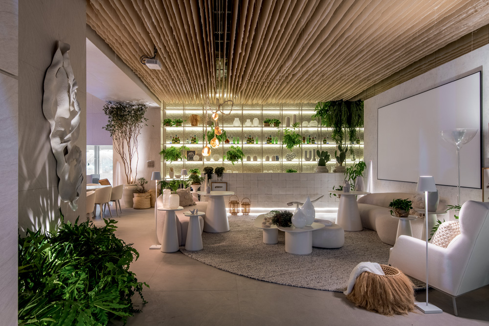 Ambiente da Casacor com teto de palha, móveis brancos e detalhes em plantas.