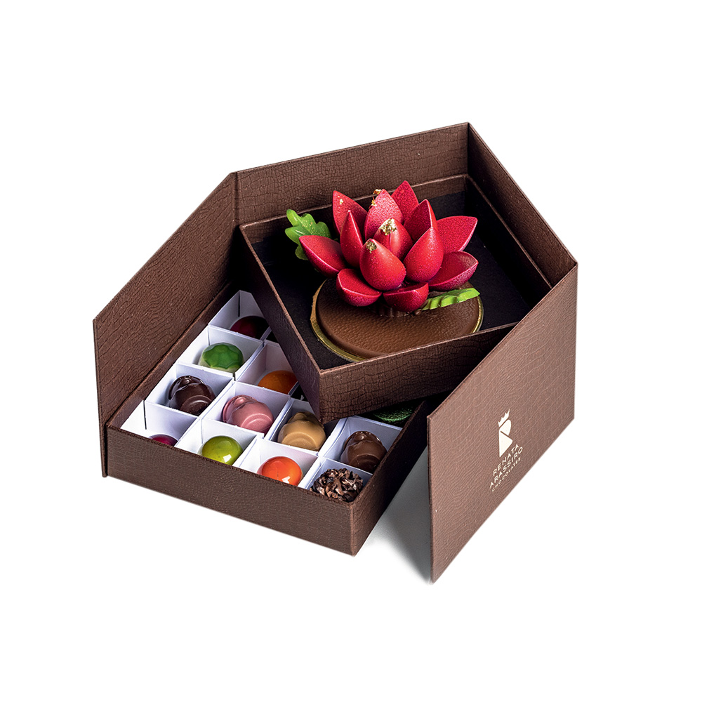 Foto still de caixa marrom de bombons coloridos com flor de lótus de chocolate.