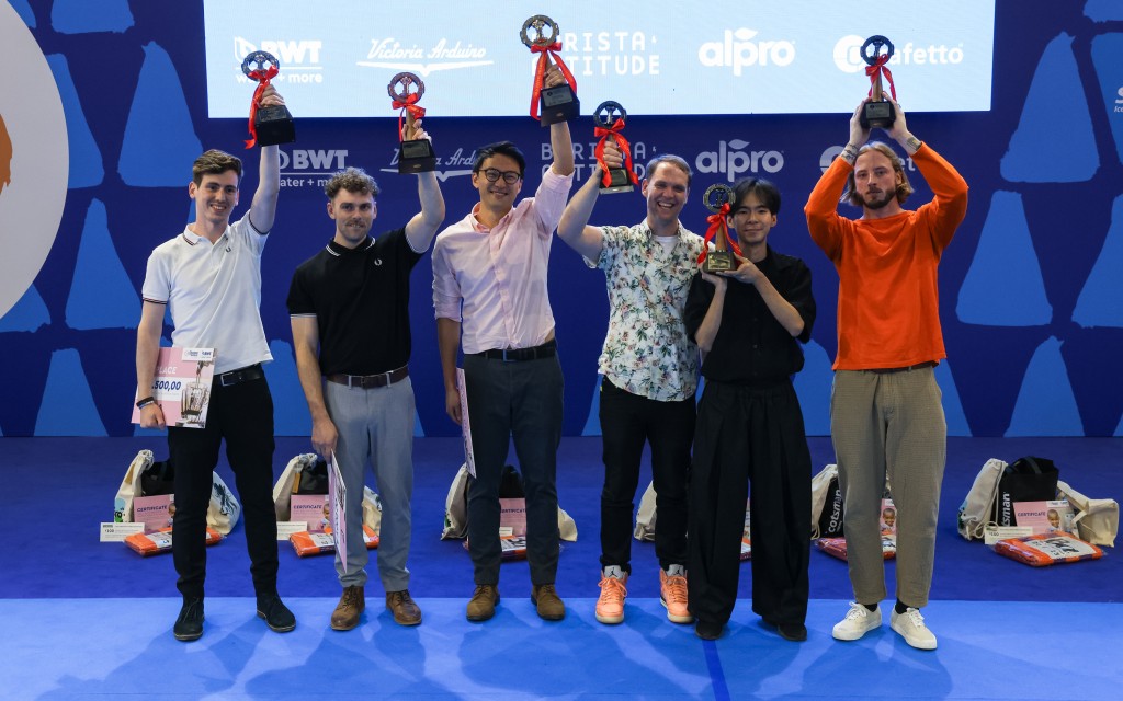 Seis pessoas alinhadas levantando troféus no World Barista Championship.