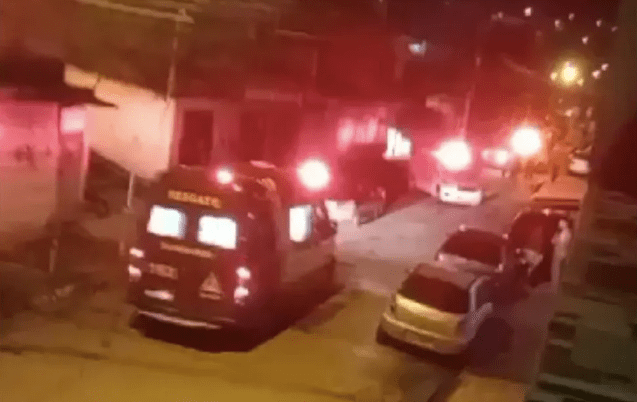a imagem mostra uma rua com uma ambulância parada e carros estacionados
