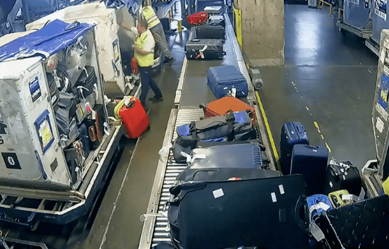 a imagem mostra uma esteira cheia de malas de viagem e alguns trabalhadores