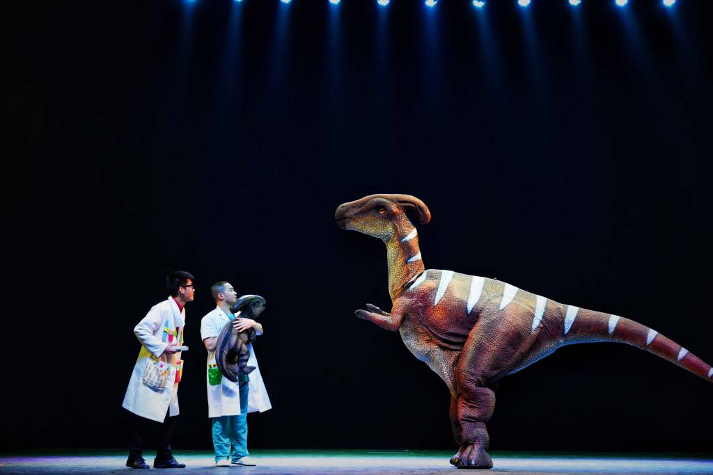 Espetáculo com duas pessoas olhando para maquete de dinossauro.