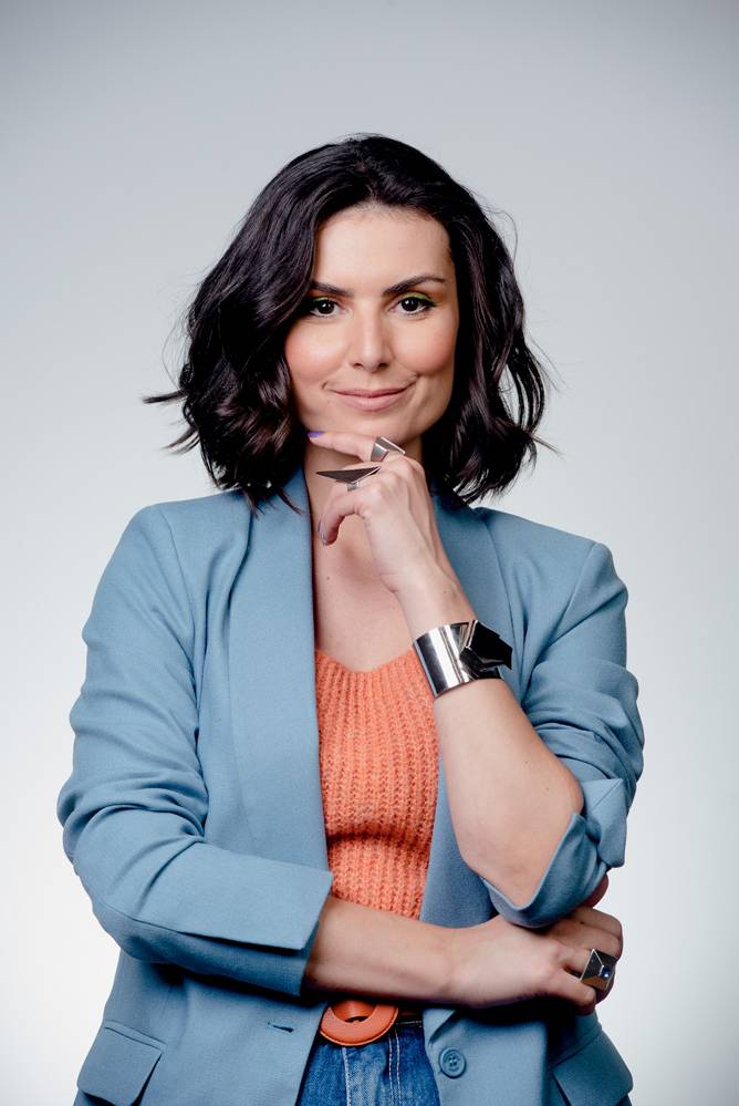 Nathalia Arcuri (Claudio Belli-Divulgação) (1).jpg Mulher branca de cabelos pretos curtos encara a câmera com um meio sorriso e uma das mãos apoiada no queixo. veste blazer azul-bebê e camiseta laranja.