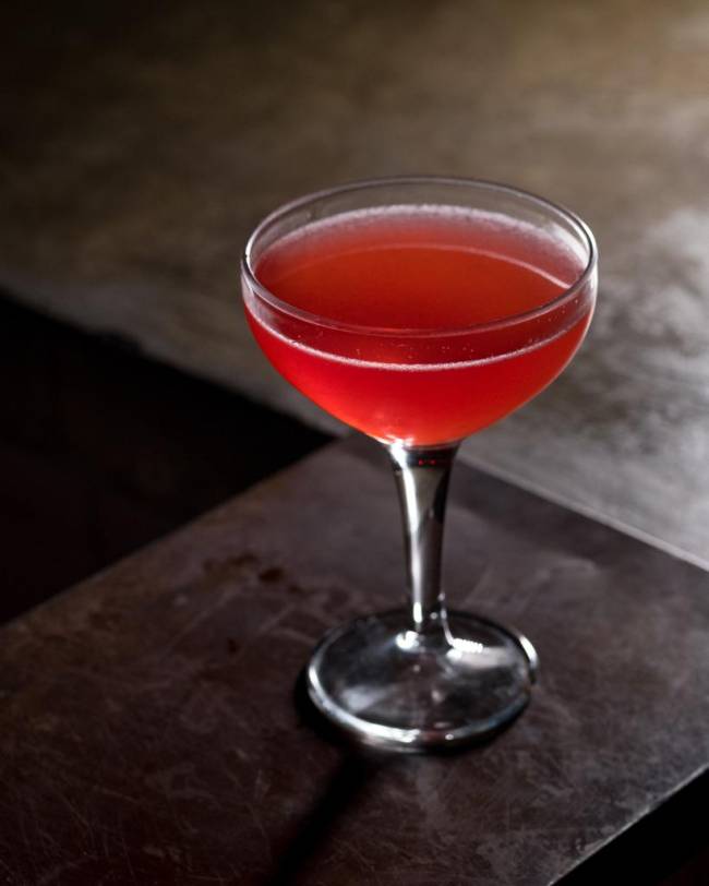 Regô Taça com drinque rosa sobre balcão cinza.