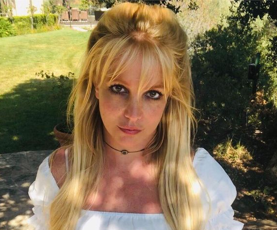 A cantora Britney Spears com os cabelos semi presos olhando séria para a câmera