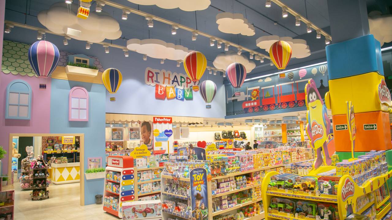 A imagem mostra o interior de uma loja de brinquedos, com diversas prateleiras e teto e paredes azuis.
