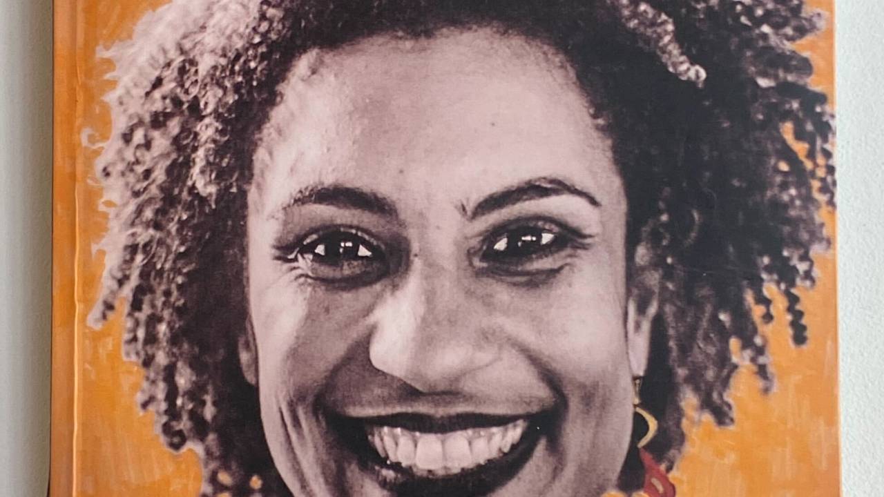 a capa do livro mostra marielle franco, uma mulher negra, de cabelos soltos, sorrindo