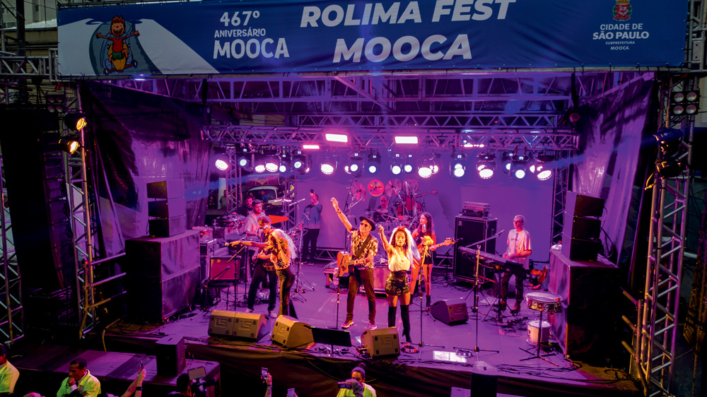 foto mostra cantores em cima de um palco tocando uma música