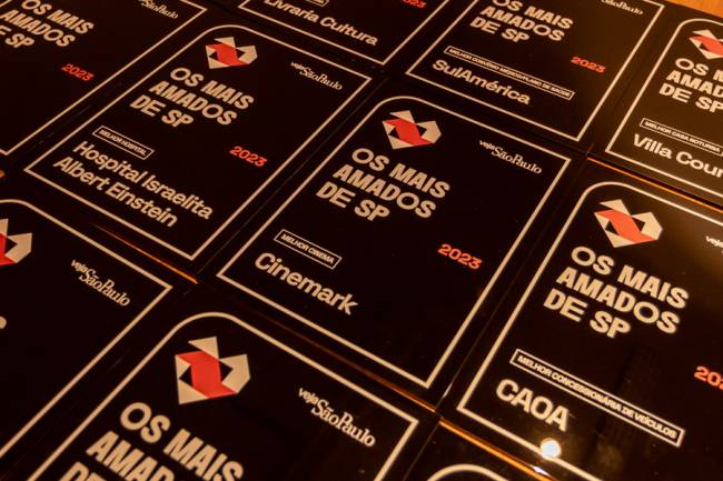 Imagem mostra cerca de 10 placas em mesa. Em casa placa, logotipo da premiação e lê-se: Os mais amados de SP 2023 Cinema: Cinemark Entre outras categorias.