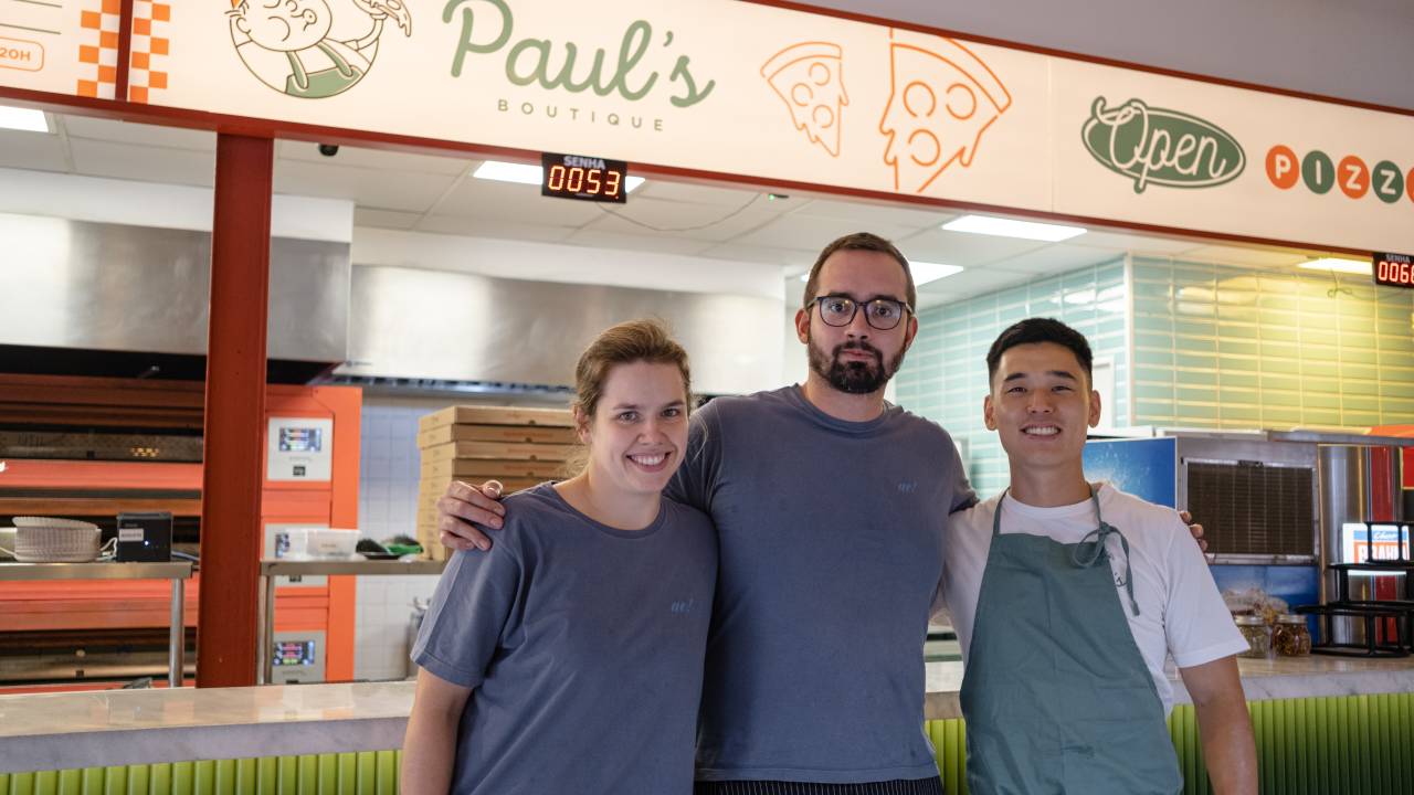 Dois homens e uma mulher postados em frente ao balcão da Paul's Boutique.