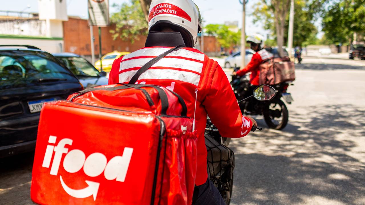 Entregador em moto com a mochila vermelha do iFood.