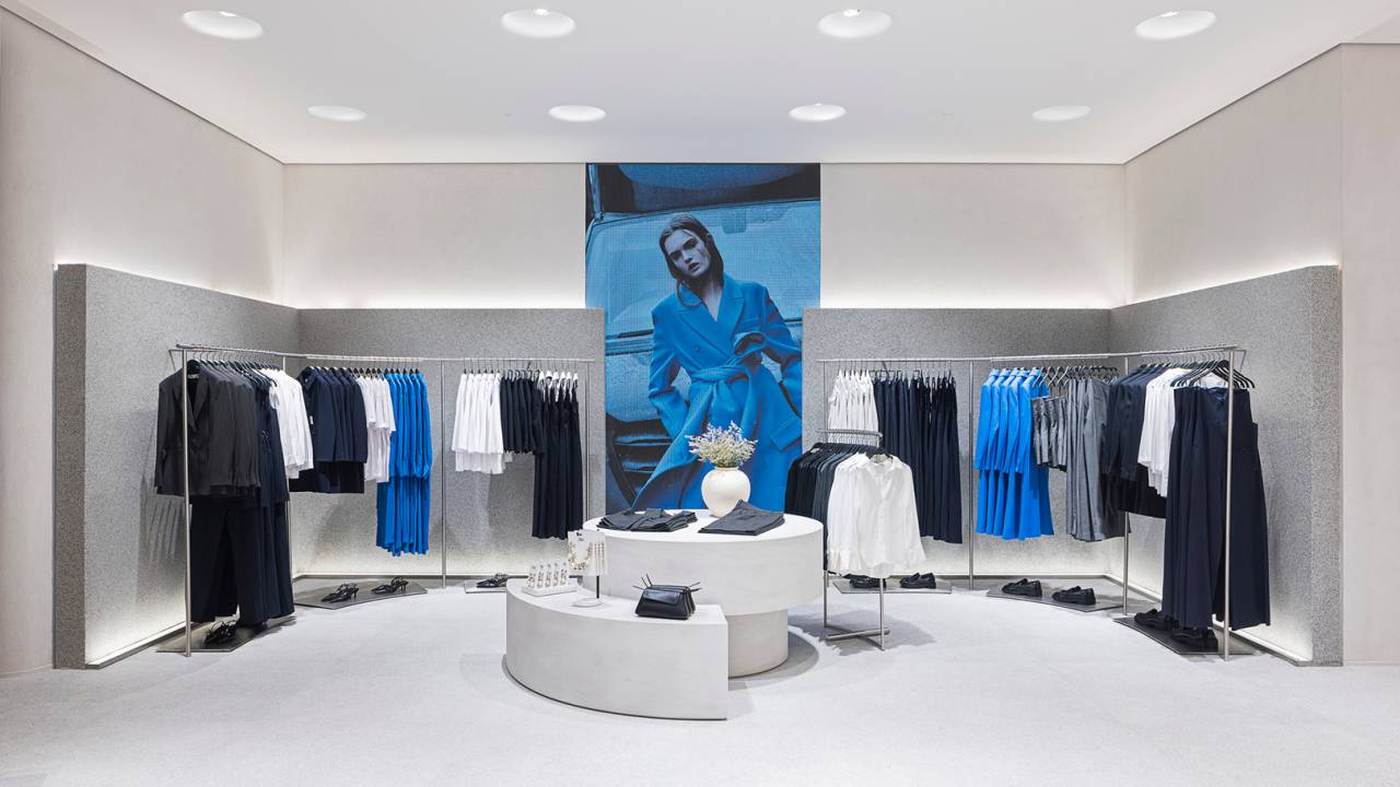 a foto mostra o interior de uma loja Zara com roupas nas araras e uma grande foto de uma modelo no centro
