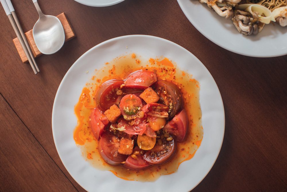 Foto aérea de prato de louça branca com salada de tomates.
