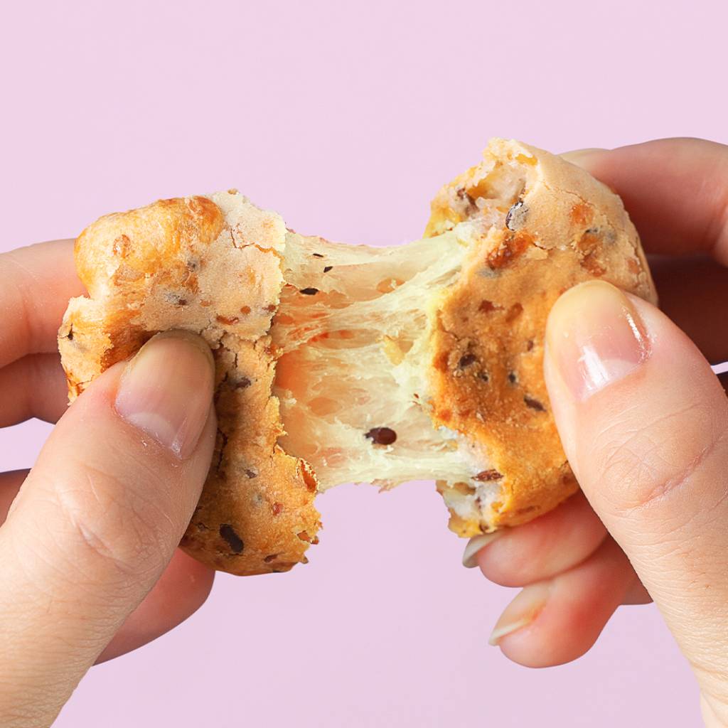 pão de queijo. tapioca – cafe zinn A imagem mostra duas mãos abrindo um pão de queijo.