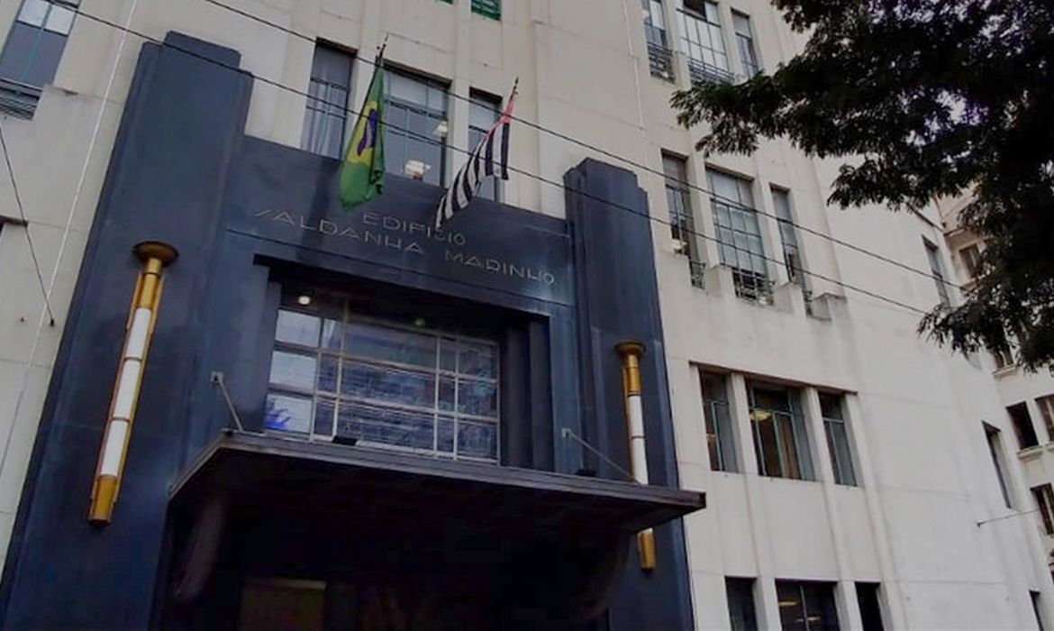 a fachada de um prédio comercial com as bandeiras do brasil e de são Paulo