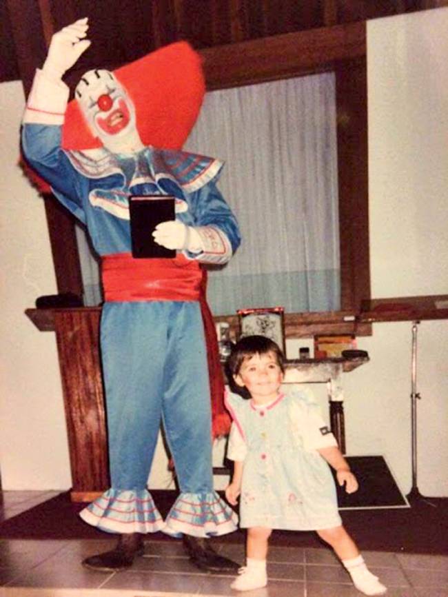 Foto antiga mostra Arlindo vestido como o palhaço Bozo e a filha, Stacy, pequena, sorrindo, com maquiagem de palhaça. Os dois estão na sala de uma casa