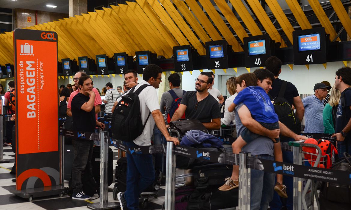 fila de aeroporto com pessoas e suas malas aguardando