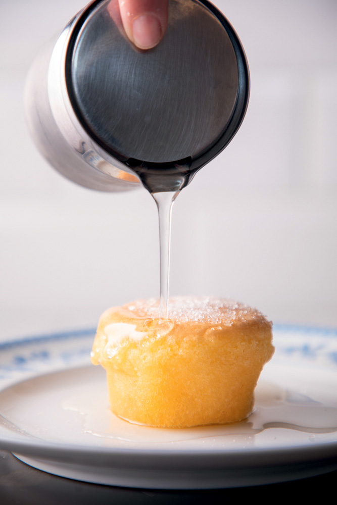 Bolinho com açúcar em cima, sobre um prato branco.