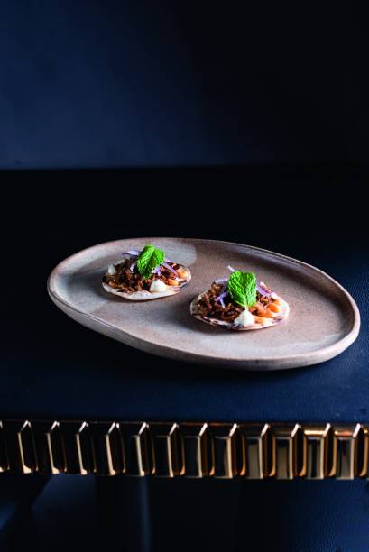 Pão ázimo: coberto de pernil de cordeiro desfiado, cebola-roxa, hortelã, queijo boursin e maionese de harissa