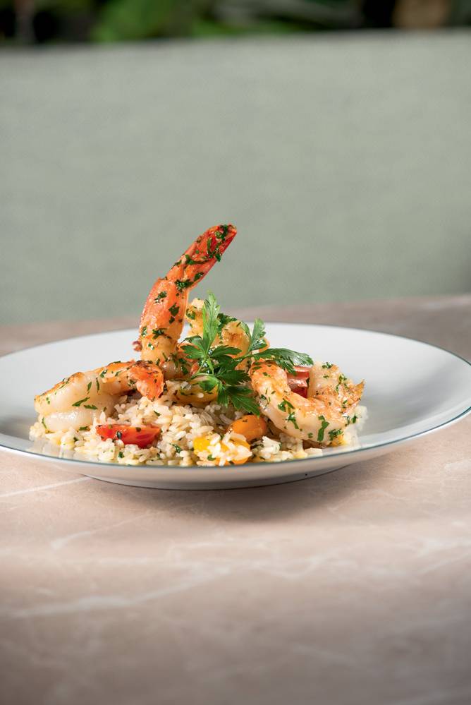 prato de louça branca com arroz com tomate coberto por camarão.