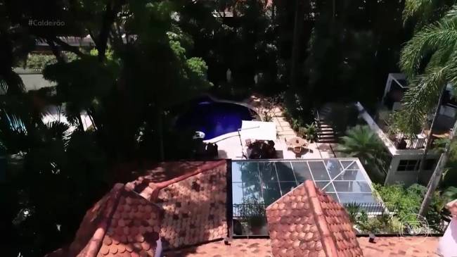 casa ana maria Imagem mostra telhado de casa e, ao fundo, piscina, rodeada de árvores